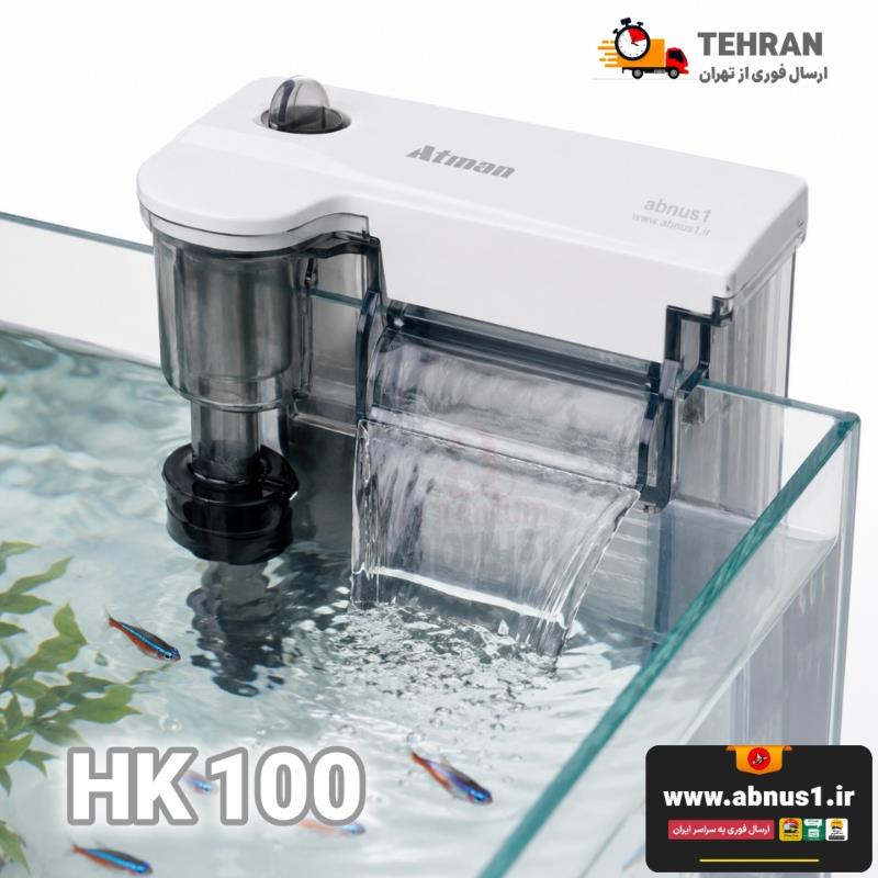تصویر محصول نشان‌دهنده بسته‌بندی رسمی فیلتر آویزان برند معتبر “Atman” مدل HK-0100 است. در نمای روی جعبه، دستگاه با بدنه شفاف و باکیفیت به نمایش درآمده که بر روی لبه آکواریوم نصب شده است. ویژگی‌های بصری مهم در عکس شامل لوله مکش مجهز به اسکیمر سطح آب (برای جمع‌آوری چربی و ضایعات سطح)، پیچ تنظیم جریان آب در قسمت بالا و خروجی آب به صورت آبشاری پهن است که علاوه بر زیبایی، به اکسیژن‌رسانی بهتر کمک می‌کند. طراحی مینیمال و ابعاد جمع‌وجور دستگاه در کنار تایپوگرافی واضح مدل کالا، حس مدرن بودن و کارایی بالا را به بیننده القا می‌کند.